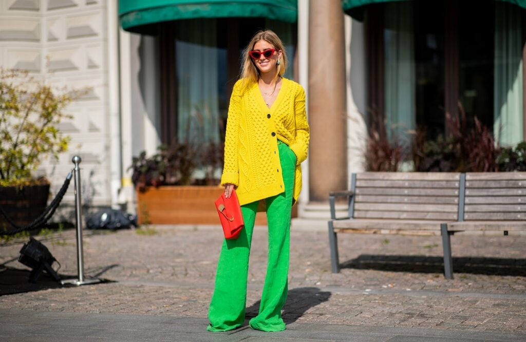 Femme en pull jaune, pantalon vert et sac à main rouge
