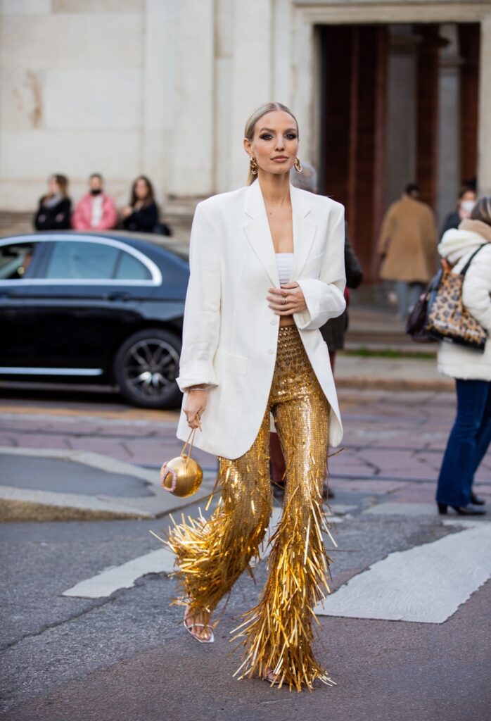 Femme en blazer blanc et pantalon doré