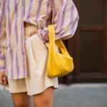 Trendsetteuse dans une chemise oversize colorée à motifs, des shorts neutres et un sac à main coloré