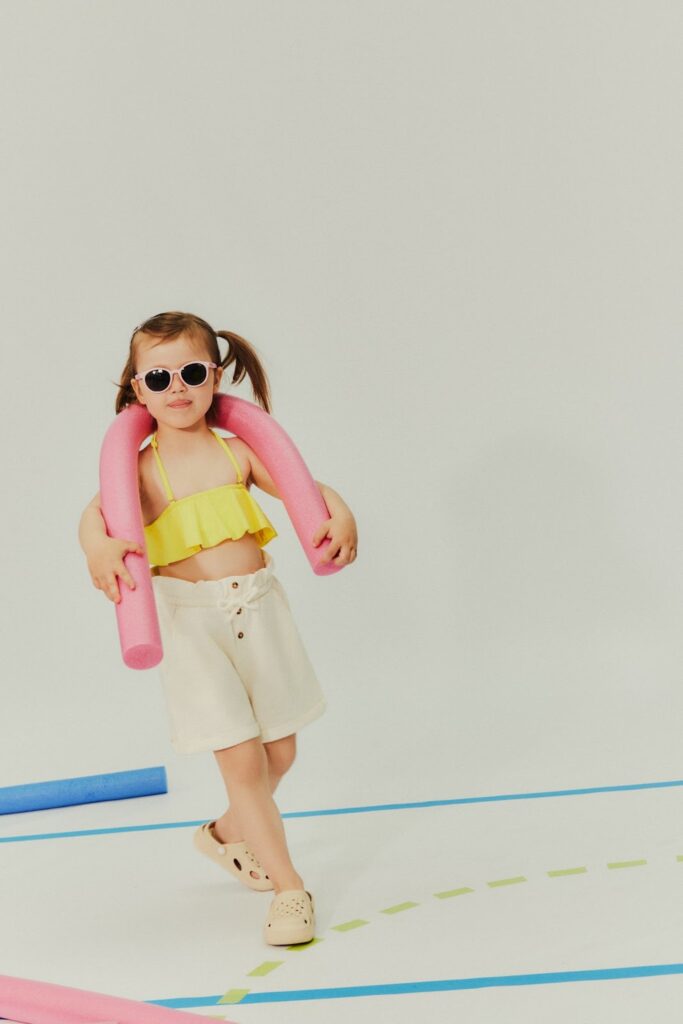 Petite fille avec des lunettes de soleil en maillot de bain jaune et short