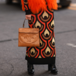 Femme vêtue d'une robe en maille à motifs et portant un sac à main Prada marron