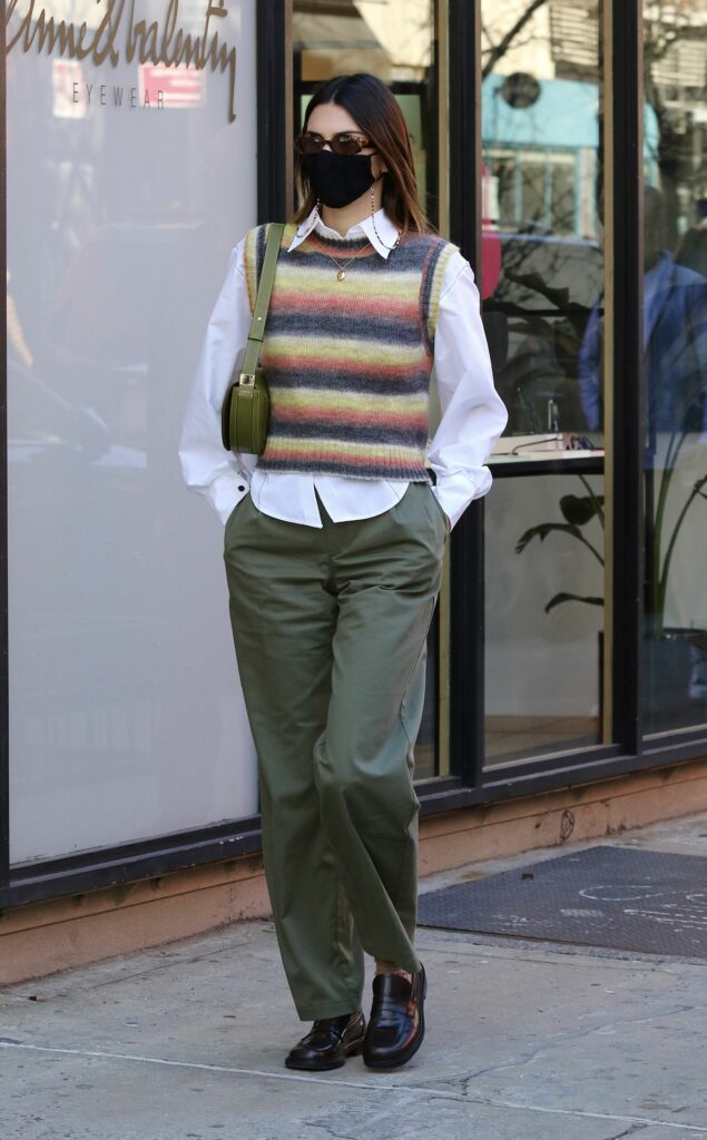 Femme en pantalon cargo vert, chemise blanche, gilet sans manche multicolore et loafers