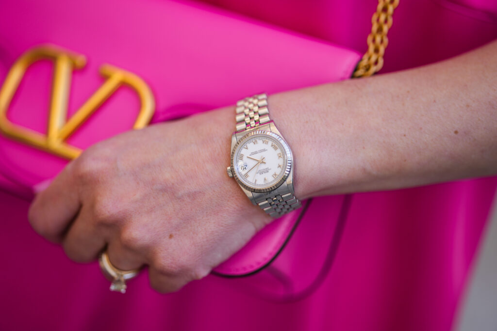 Montre à bracelet argenté sur fond de sac à main rose