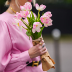 Femme en blouse rose tenant un bouquet de fleurs dans la main