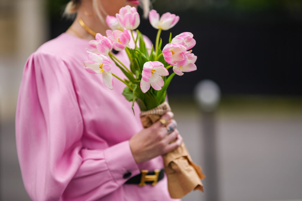 Femme en blouse rose tenant un bouquet de fleurs dans la main