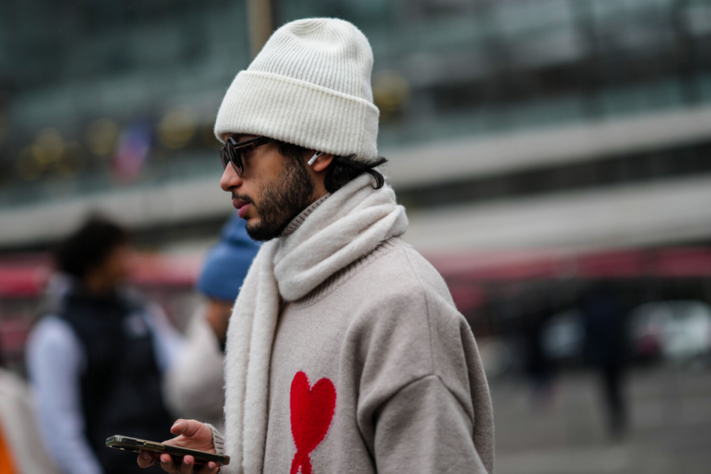 Homme portant un pull couleur café et lait avec un cœur et un chapeau blanc