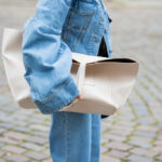 Femme dans un look denim et avec un sac à main beige