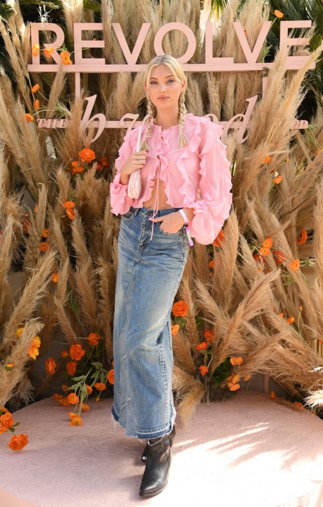 Look de festival dans le style country avec une chemise rose à volants, une jupe en jean maxi et des santiags