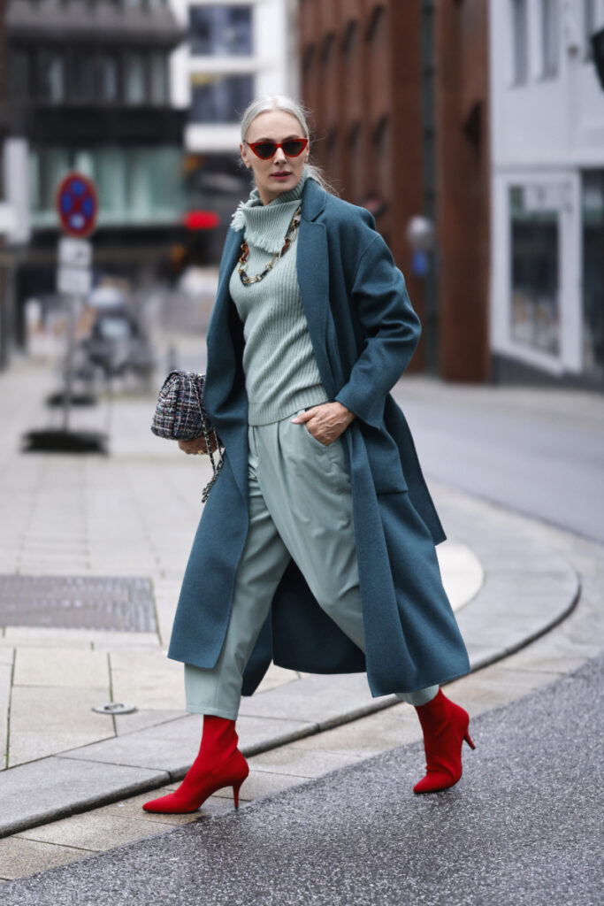 femme portant un manteau bleu pétrole et des chaussures rouges